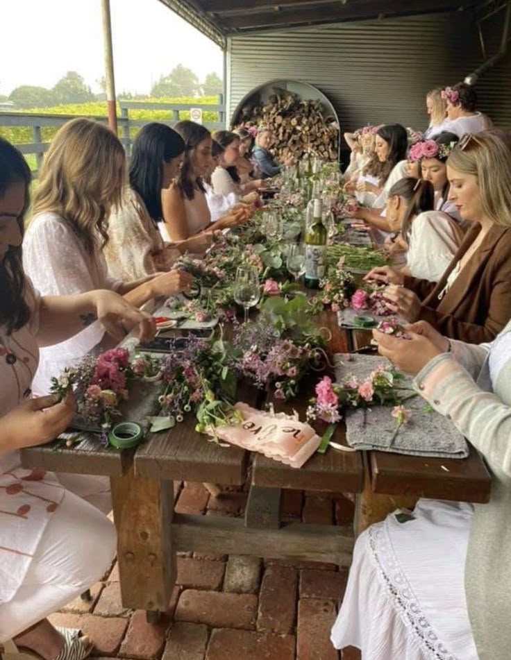 Mulheres reunidas em uma vivência com flores ao redor de uma mesa
